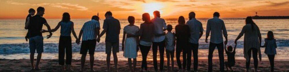 Group of people silhouetted against a stunning sunset at the beach, illustrating the serene end to a perfect cruise day.