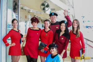 Group of people dressed in Star Trek-themed costumes on a cruise ship deck, smiling and posing for a photo, reflecting a fun themed group cruise experience.