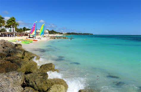 Beautiful beach with turquoise waters and colorful sailboats in the Bahamas.