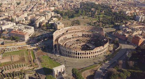 Aerial view of the Colosseum in Rome surrounded by city buildings and greenery