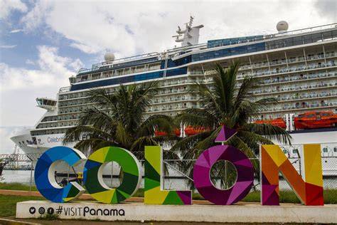 Cruise ship docked in Colón, Panama with colorful Colón sign and palm trees in the foreground