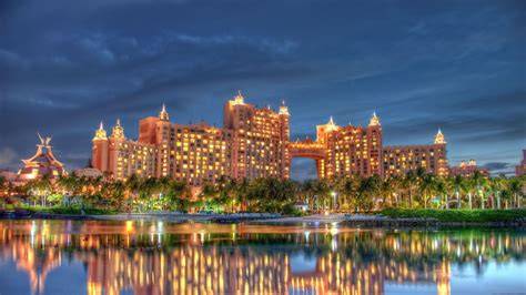 Illuminated resort buildings reflecting in the water at night.