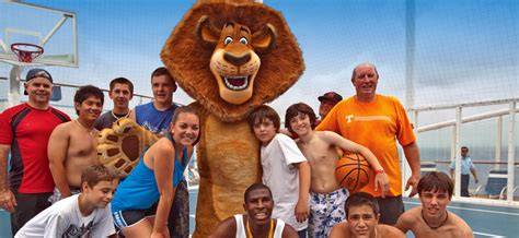 Joyful group playing basketball with an animated lion character on a cruise ship deck under a clear sky.