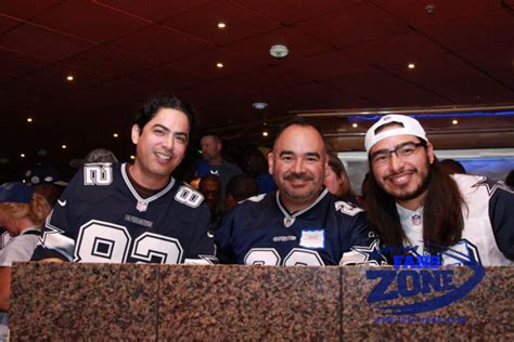 Three sports fans in team jerseys enjoying a themed cruise event onboard a ship.