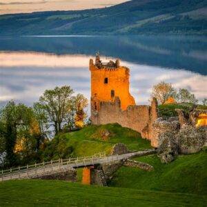 Ancient castle ruins overlooking a serene lake at sunset