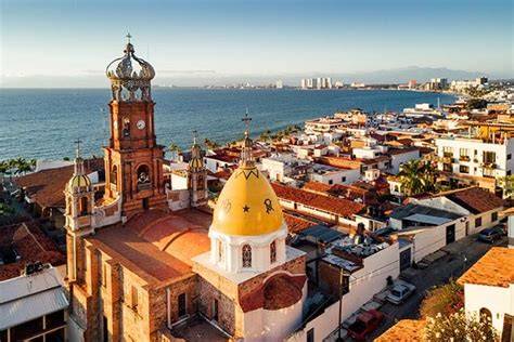 Aerial view of a coastal city with historic buildings and a prominent church, overlooking the ocean.