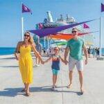 Family walking on the pier with a cruise ship docked in the background during a tropical getaway in the Bahamas.