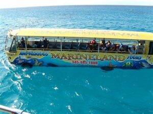 An amphibious tour vehicle filled with tourists, floating on clear blue ocean waters during a marine adventure tour.