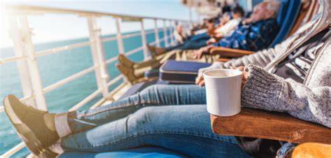 Relaxed traveler enjoying a sunny day on a cruise ship deck overlooking the ocean, with coffee in hand