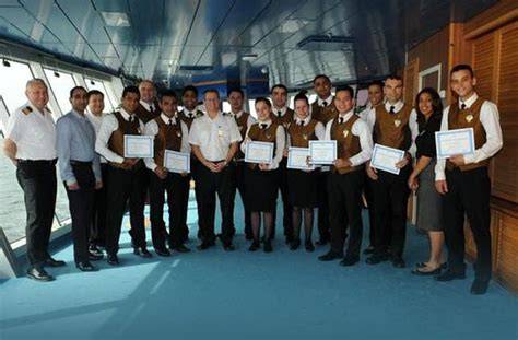 Cruise ship staff and crew holding certificates in a group photo.