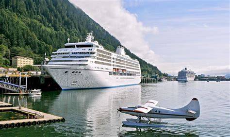 Luxury cruise ship docked at a scenic port with a seaplane on the water in Alaska