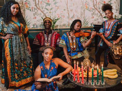 Group of people in traditional African attire celebrating Kwanzaa with candles, fruits, and cultural items.