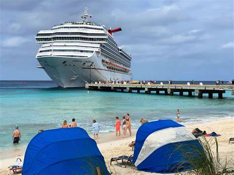 Cruise ship docked at a beach with blue beach tents and people enjoying the water in Turks and Caicos.