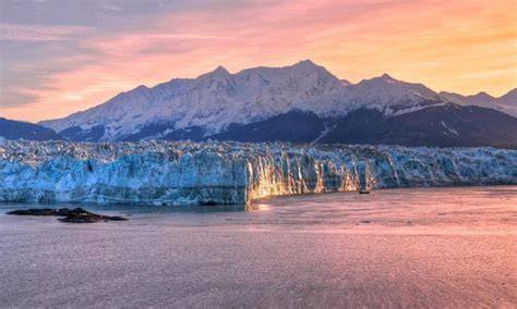 Stunning view of a glacier with snow-capped mountains at sunset.