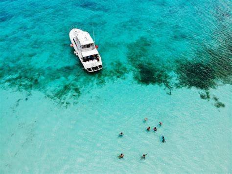 Aerial view of a boat anchored in clear turquoise waters with people swimming nearby