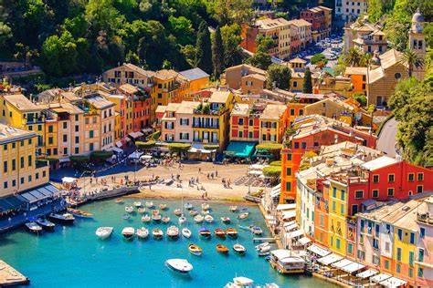 Colorful port town with boats docked at a marina, featuring vibrant buildings and clear blue water.