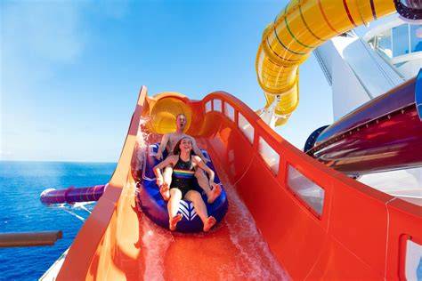 Guests enjoying a water slide on a cruise ship with clear blue ocean in the background