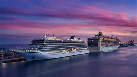 Passengers disembarking from two luxurious cruise ships docked at port during a sunset