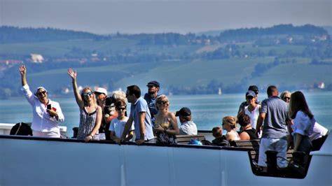 Group of people enjoying a scenic boat ride on a river with green hills in the background.