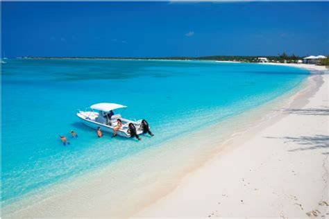 Family enjoying a day on a boat in the clear turquoise waters and white sandy beach of the Bahamas.