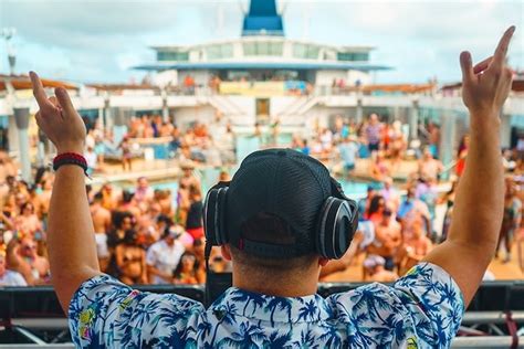 DJ playing music at a pool party on a cruise ship with a lively crowd dancing and enjoying the event.