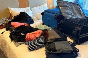 Packed suitcases and travel essentials on a bed in a cruise ship cabin