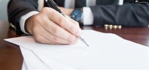 Business person signing documents with a pen