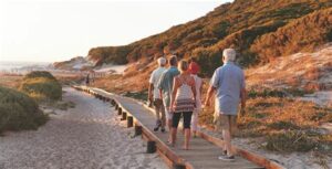 Group of people walking along a boardwalk on a beach at sunset