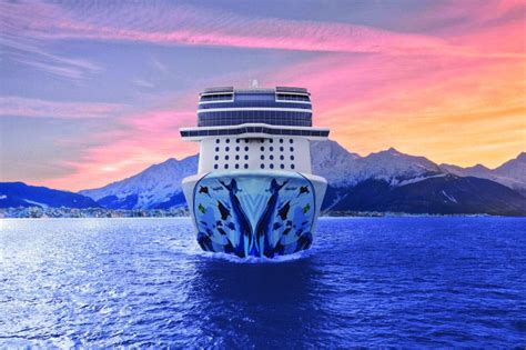 Cruise ship sailing towards the horizon with a colorful sunset and mountains in the background.