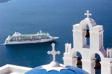 Cruise ship sailing near the iconic white architecture of a Mediterranean coastal town