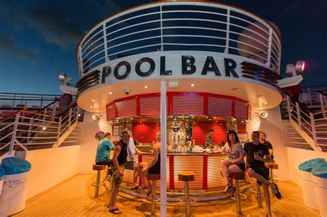 People enjoying drinks at a pool bar onboard a cruise ship during the evening