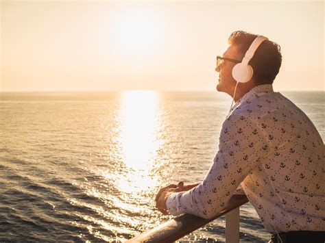 Man wearing headphones enjoying the sunset on a cruise ship deck