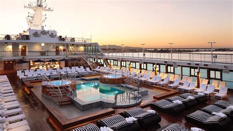 Luxury cruise ship pool deck at sunset with sun loungers and pool