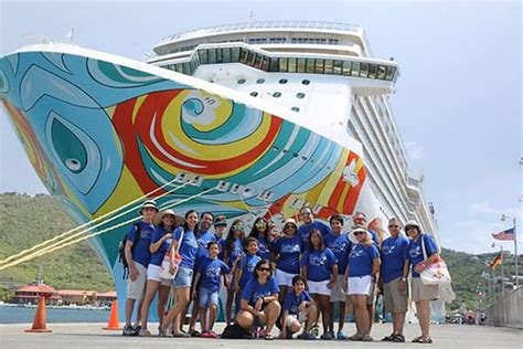 Group of people posing in front of a colorful cruise ship at a port