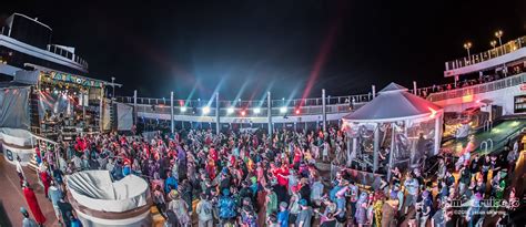 Crowded cruise ship deck at night with a lively event and bright lights