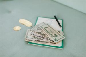 Money and notebook with a pen for planning a travel budget.