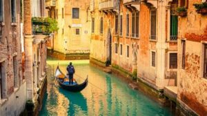 Gondolier navigating a gondola through a picturesque canal in Venice, Italy.