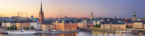 Panoramic view of Stockholm's waterfront with historic buildings and a cruise ship at sunset.