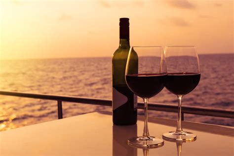 Two glasses of wine and a bottle on a table with a sunset ocean view