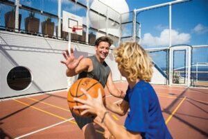 Father and son playing basketball on a cruise ship sports court