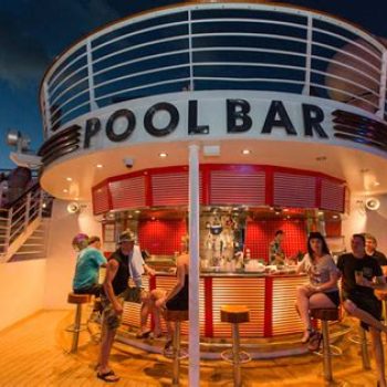 People enjoying drinks at a pool bar onboard a cruise ship during the evening