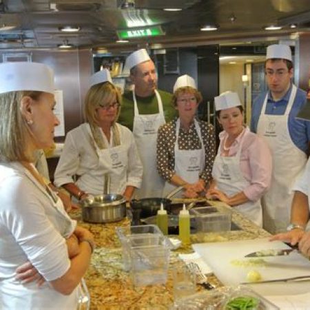 Guests participating in a cooking class led by a chef on a luxury cruise ship.